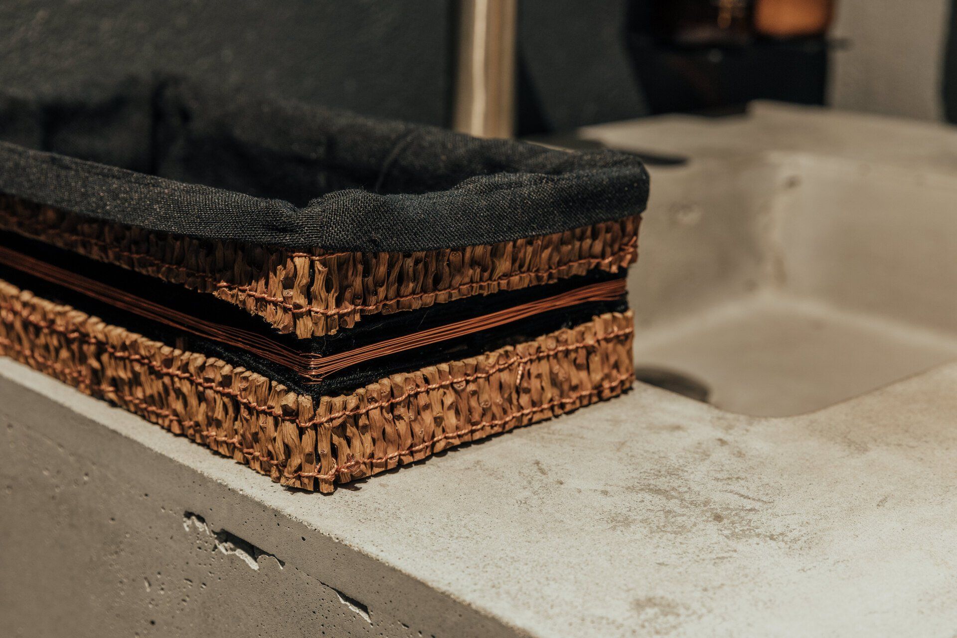 Una cesta de mimbre está sobre un mostrador al lado de un fregadero.