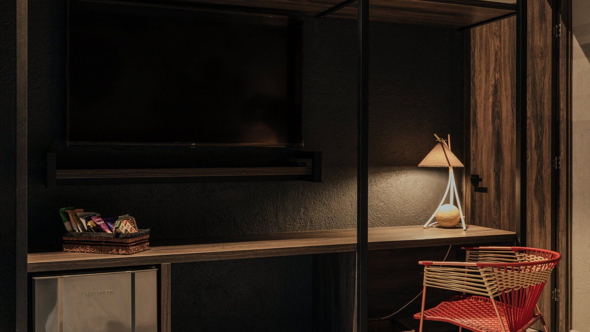 Una habitación con escritorio, silla, televisión y lámpara.