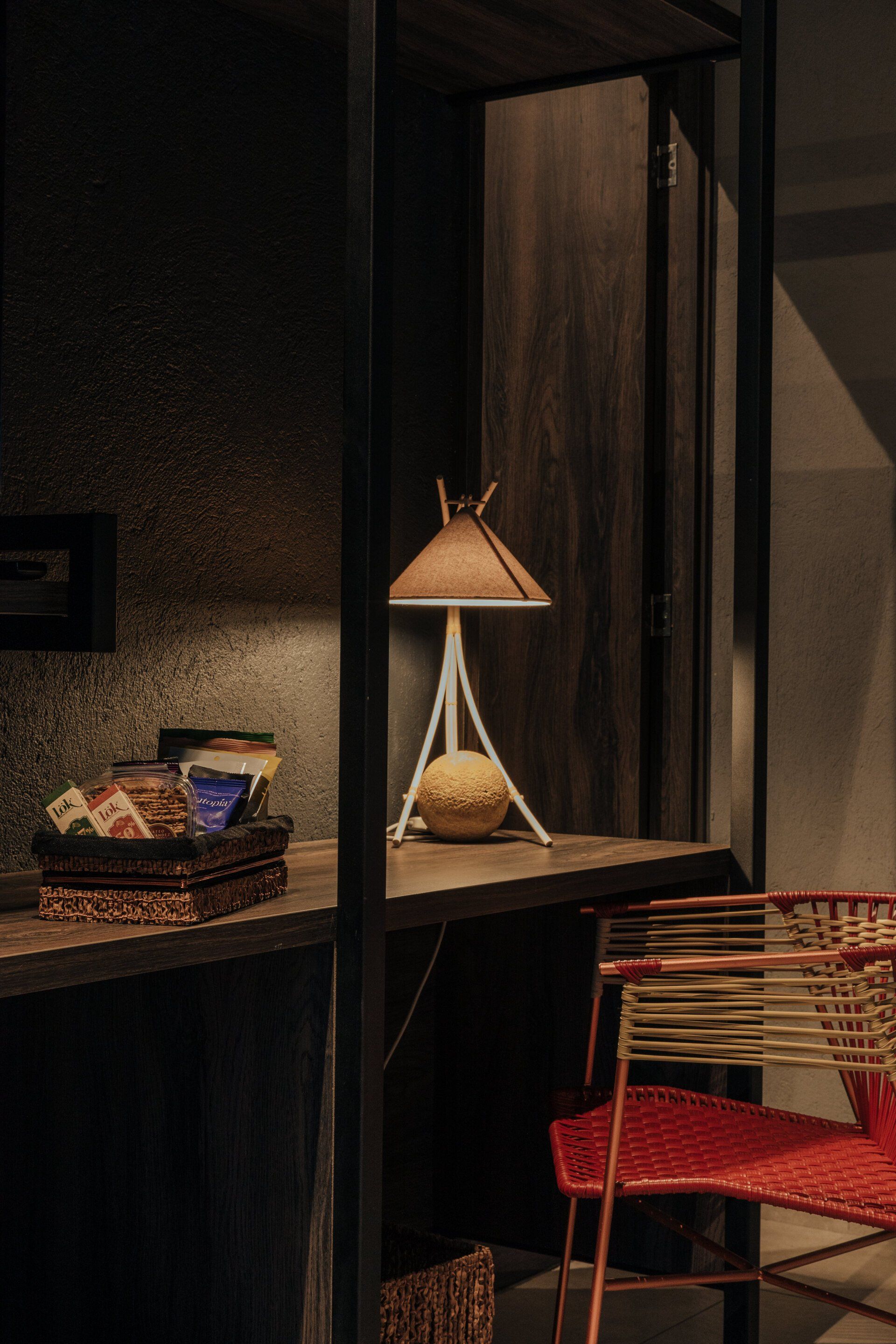 Una lámpara está sobre una mesa al lado de una silla en una habitación oscura.