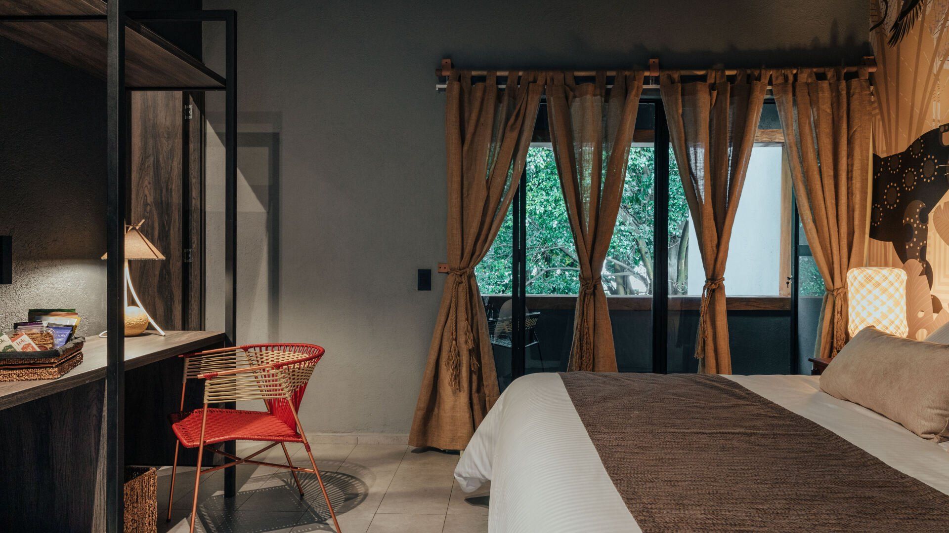 Un dormitorio con cama, silla, escritorio y ventana.