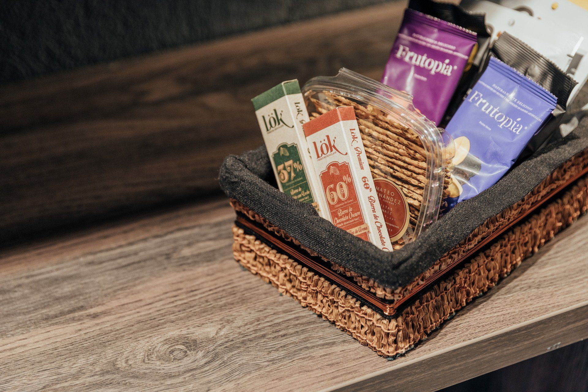 Una cesta llena de bocadillos está sobre una mesa de madera.