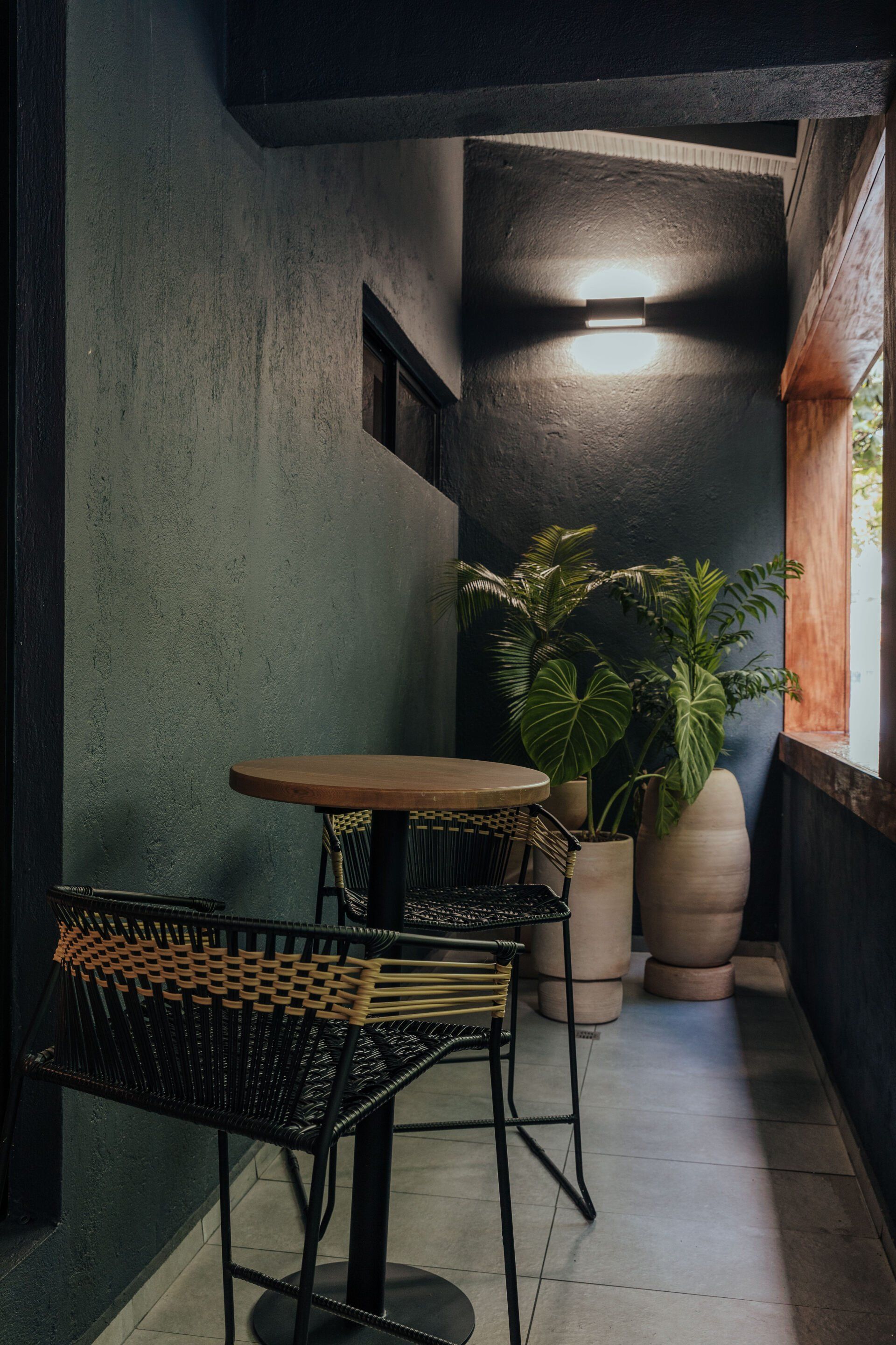 Un balcón con mesa y sillas y plantas en macetas.