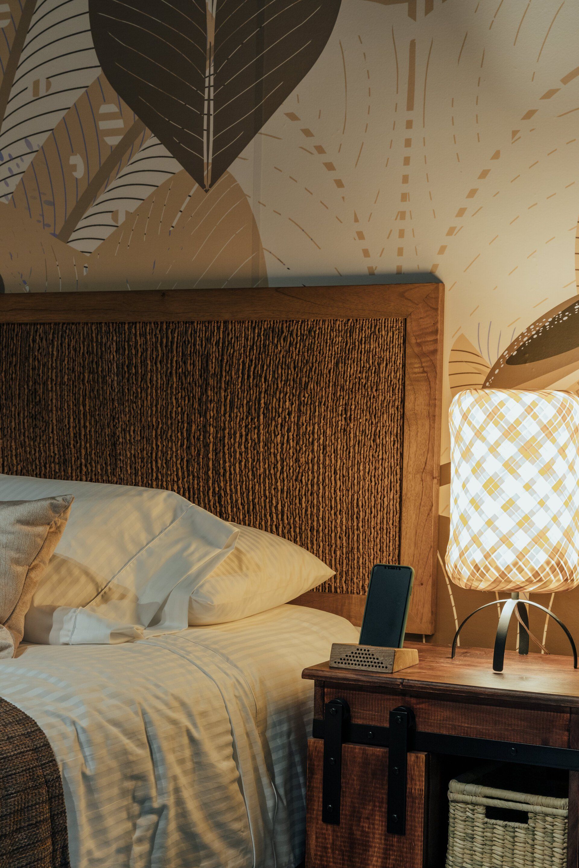 Un dormitorio con cama, mesita de noche, lámpara y teléfono.