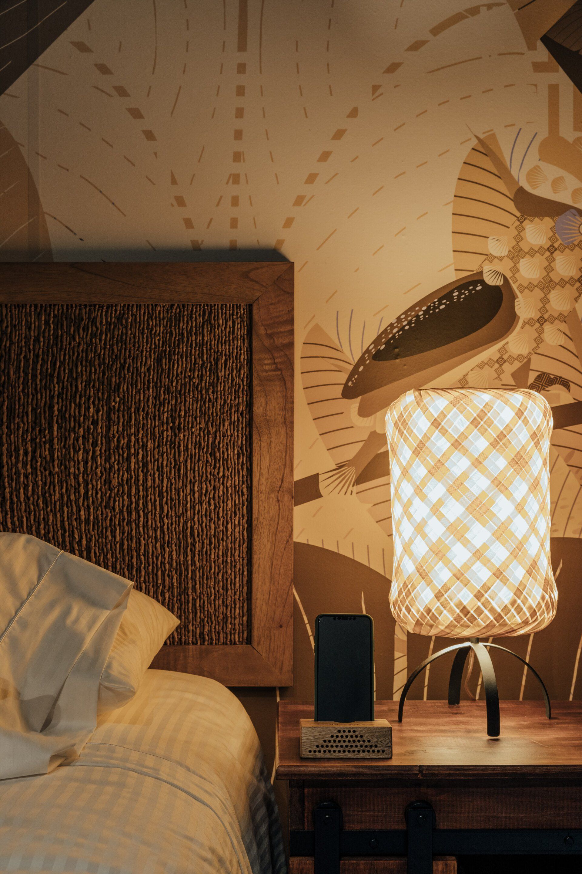 Un dormitorio con una cama y una mesita de noche con una lámpara encima.