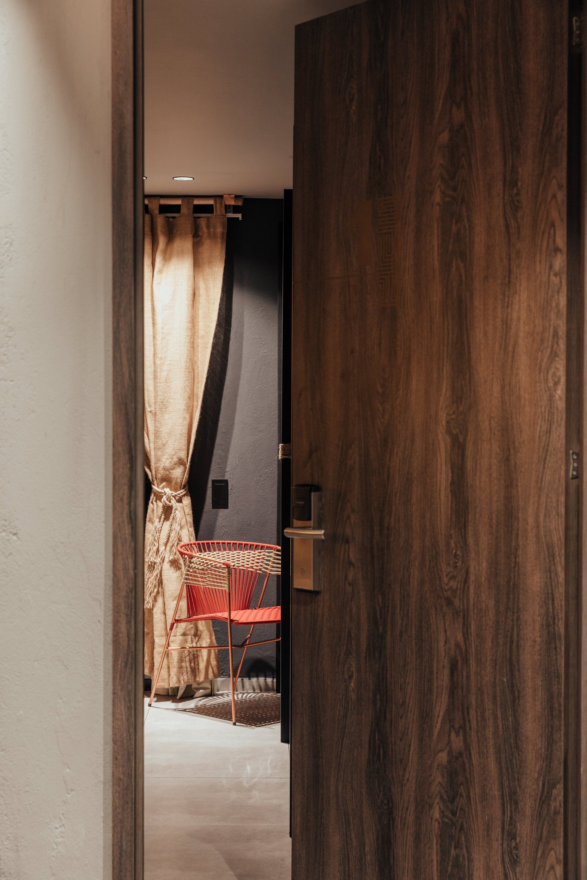 Una puerta de madera se abre a una habitación con una silla y una mesa.