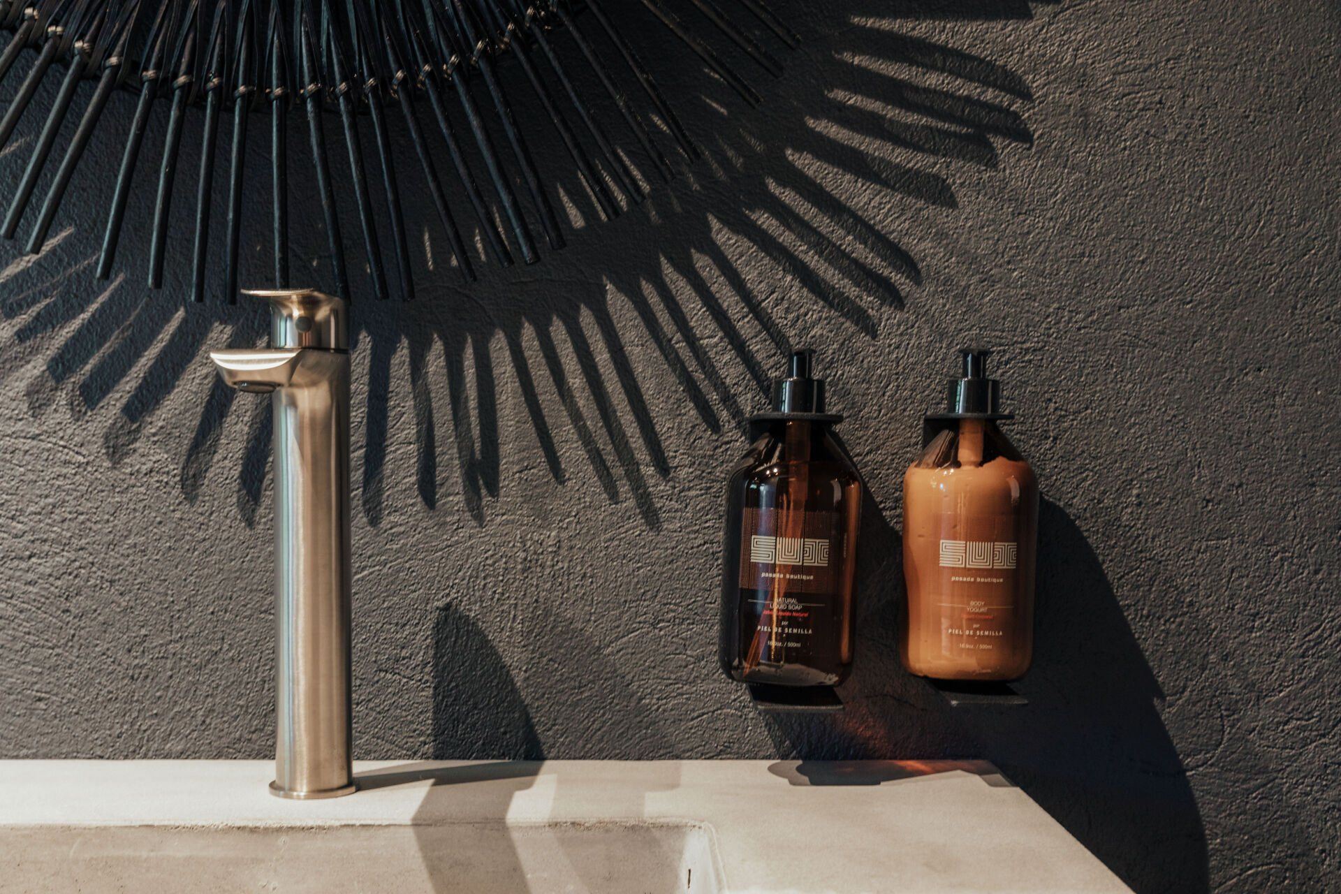 Un lavabo de baño con dos botellas de jabón colgadas en la pared.