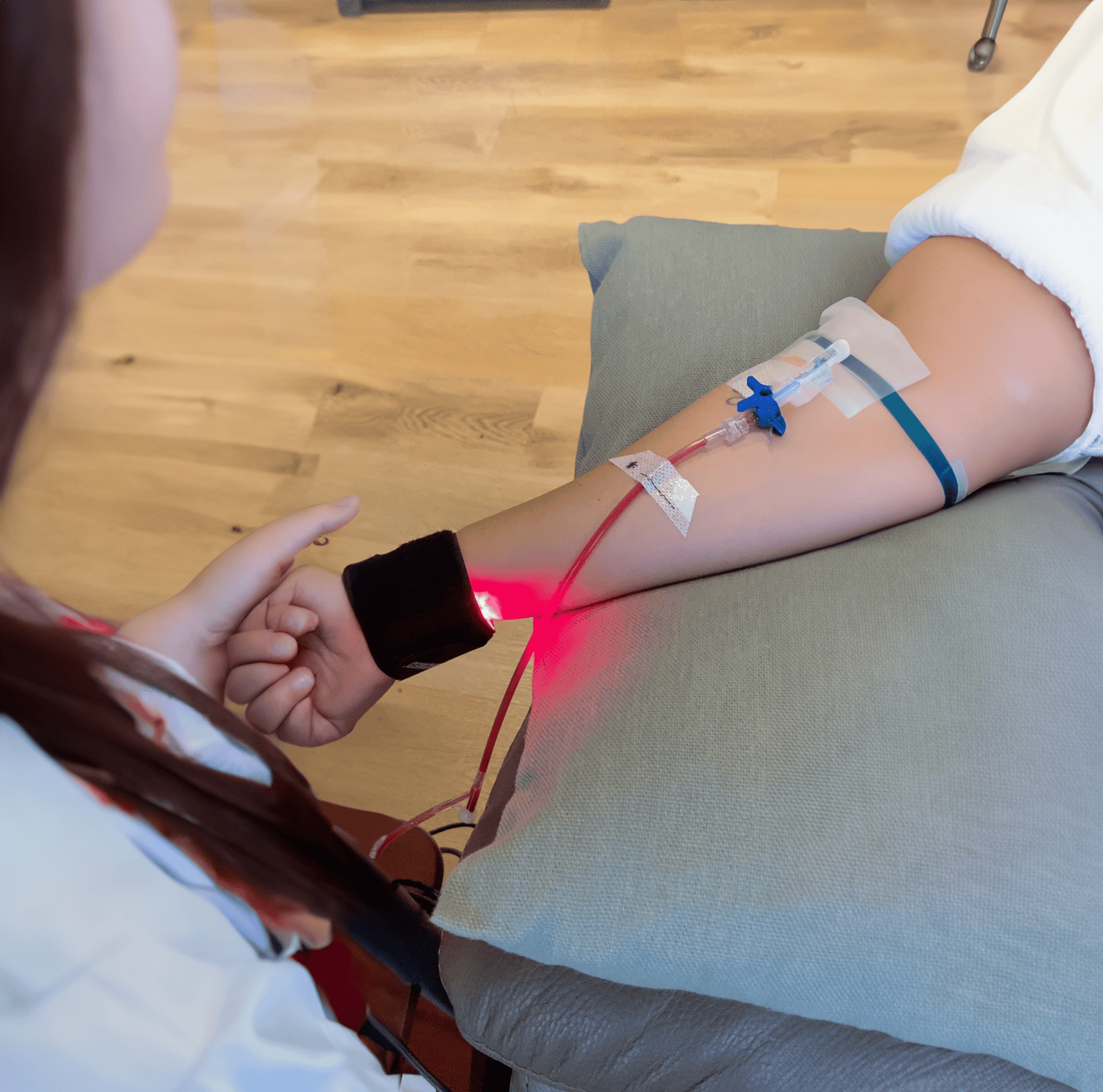 Una persona está sentada en un sofá con una vía intravenosa en el brazo.