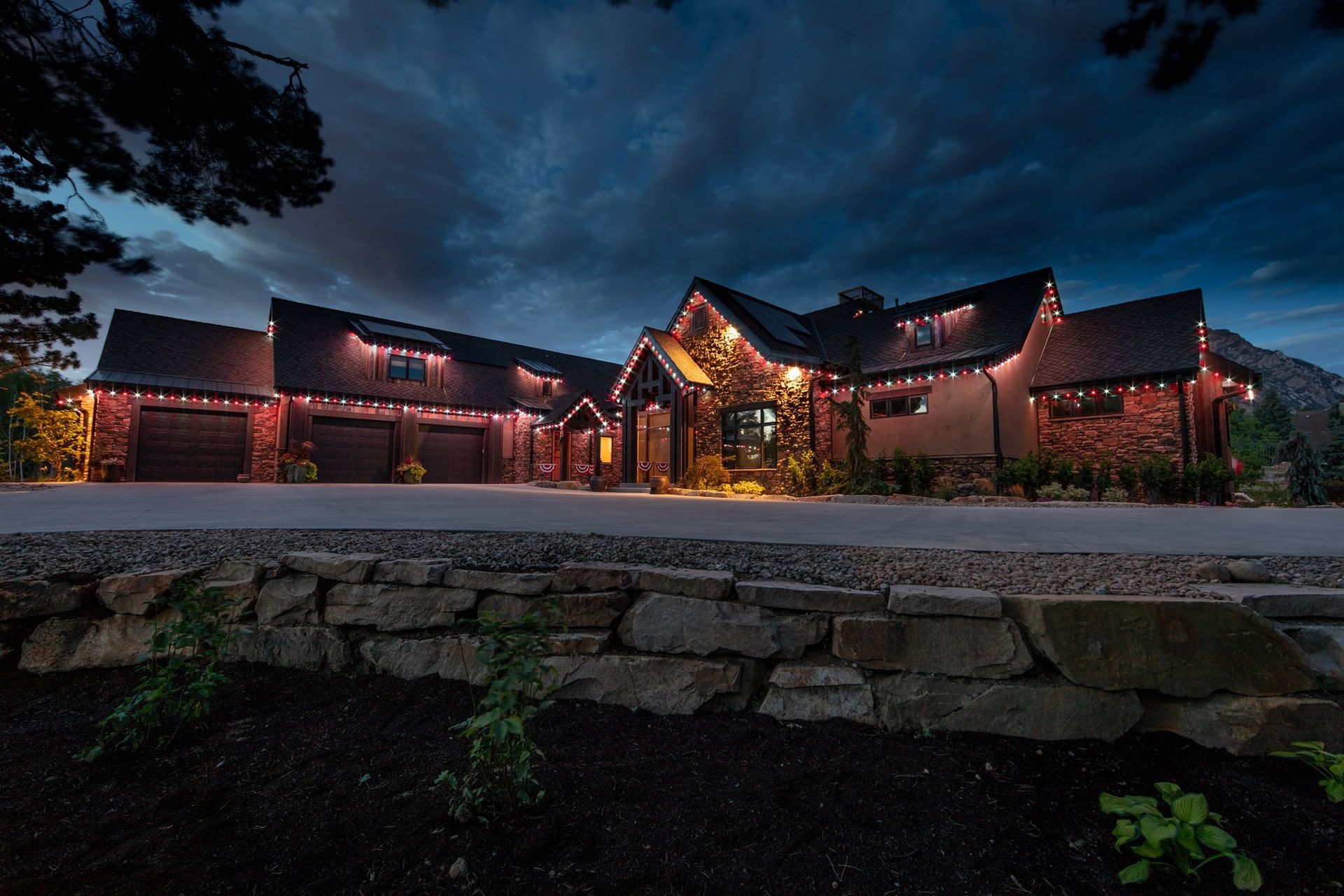 A large house with christmas lights on it is lit up at night.