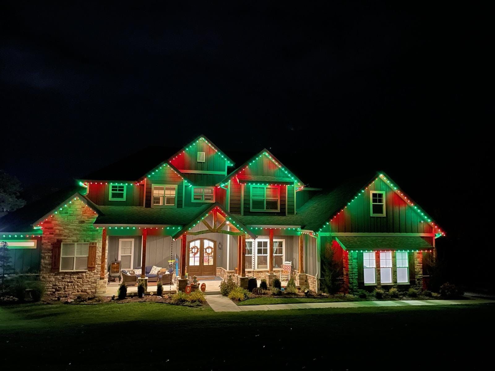A large house is decorated with red and green christmas lights.