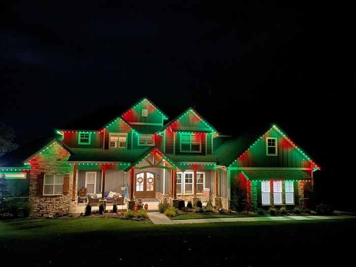 A large house is decorated with red and green christmas lights.