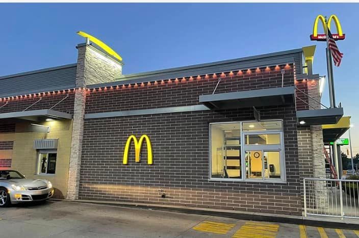 A white car is parked in front of a mcdonald 's