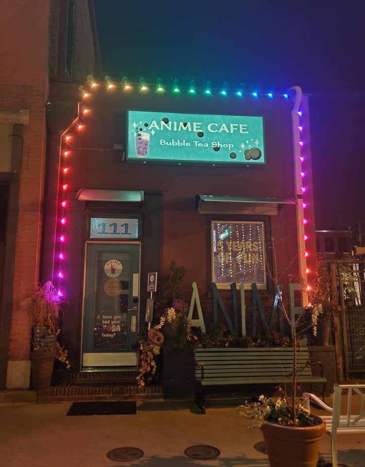 A building with a sign that says anime cafe is lit up at night.
