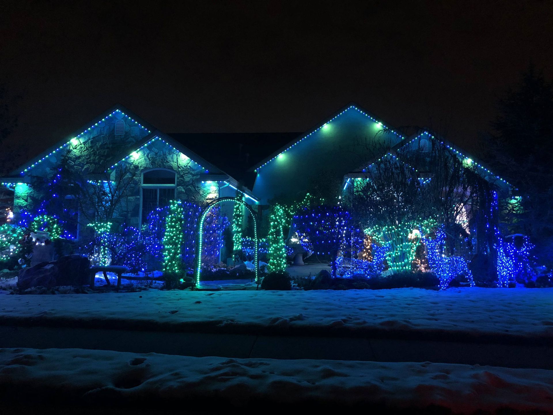 A house is decorated with blue and green christmas lights