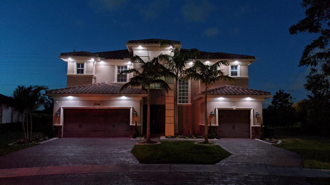 A large house with two garages is lit up at night