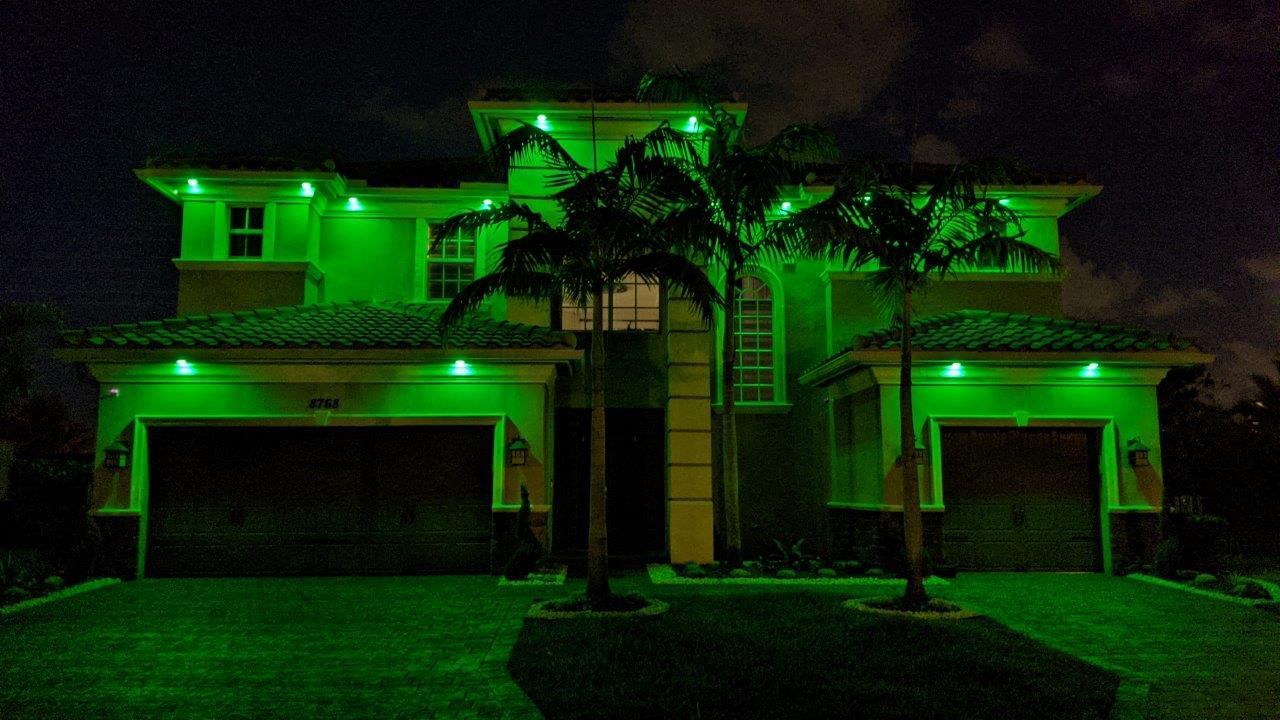 A large house is lit up with green lights at night.