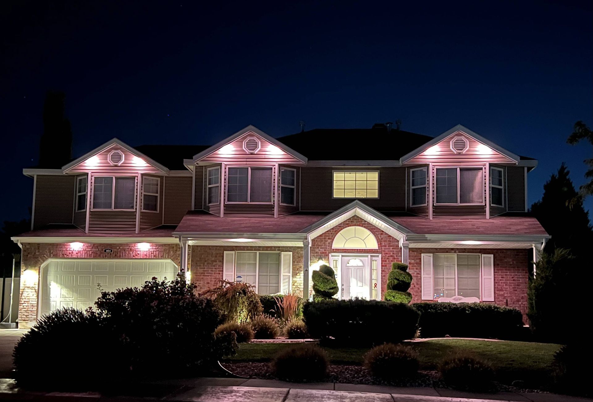 A large brick house is lit up at night