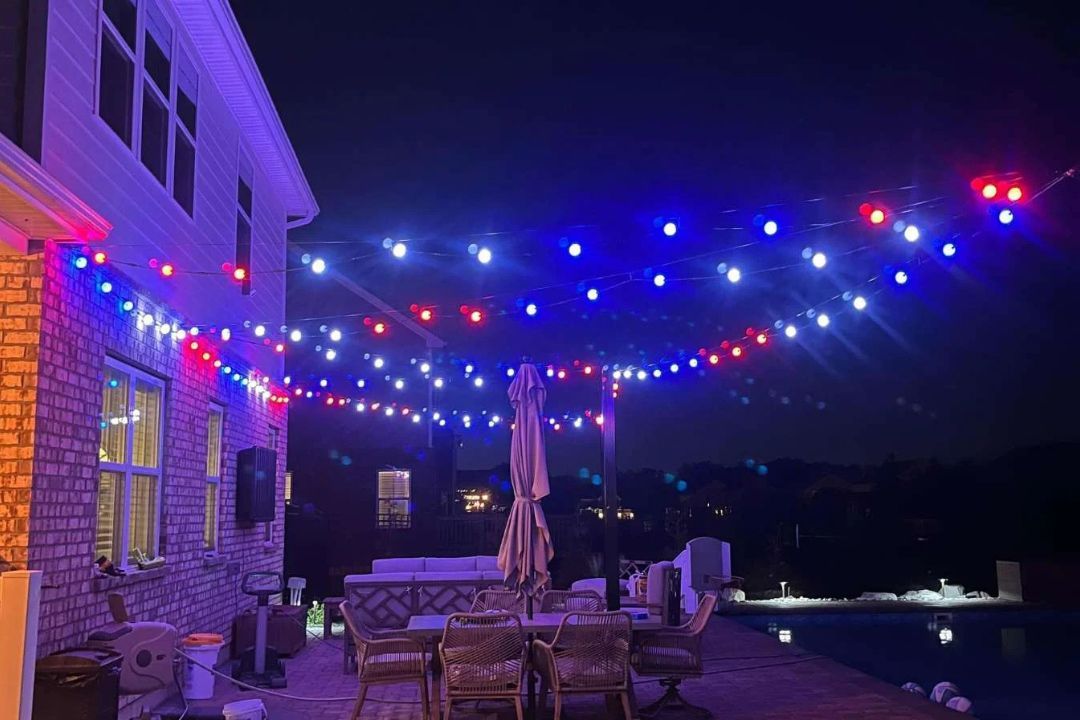 A patio with red , white and blue lights hanging from the ceiling.