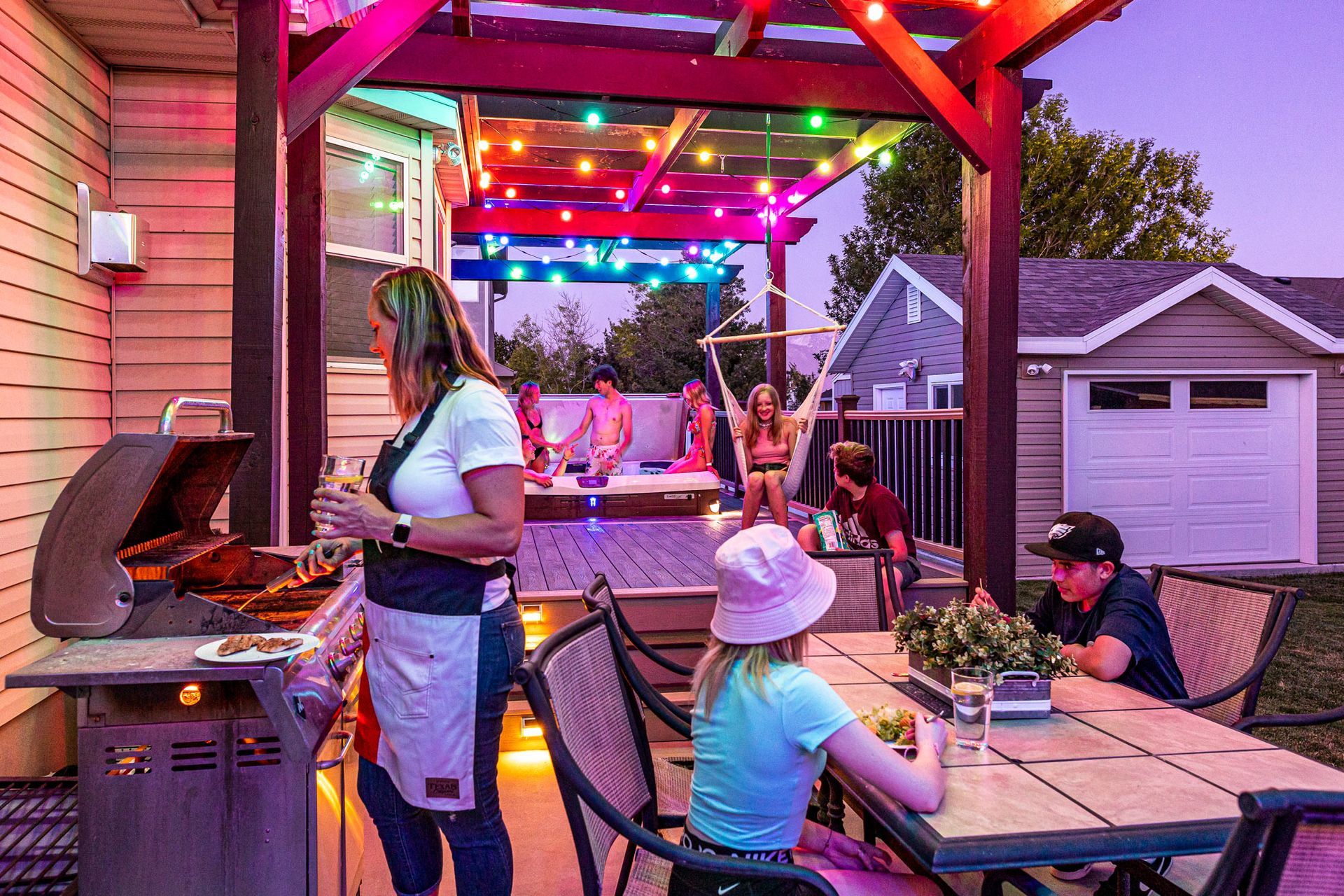 A group of people are sitting at a table under a pergola.