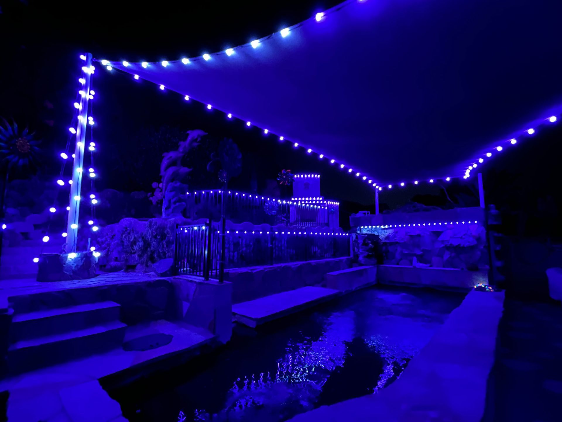 A swimming pool is lit up with blue lights at night.