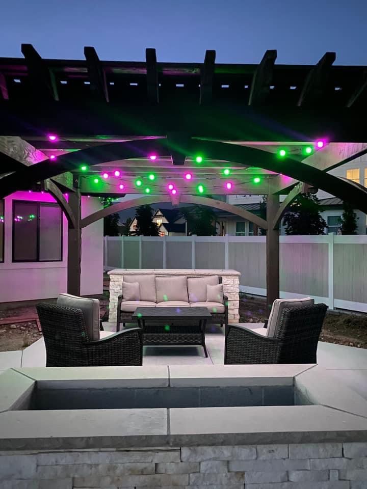 A patio with a couch , chairs , and a table under a pergola.