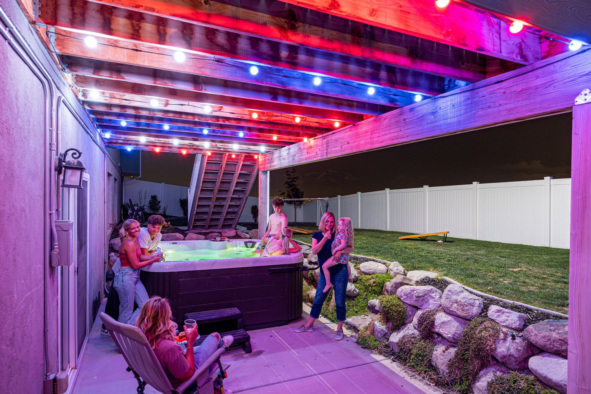 A group of people are standing around a hot tub on a patio.