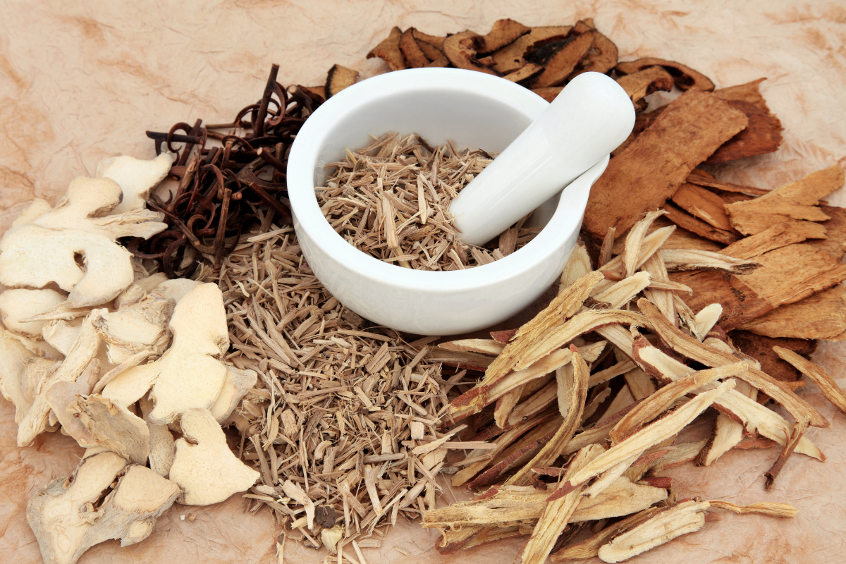 a mortar and pestle surrounded by dried herbs on a table