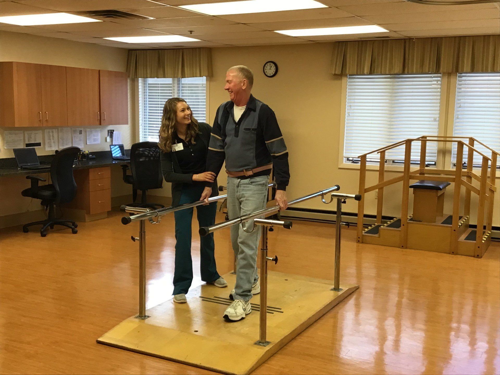 Female nurse rehabilitates middle-aged male on parallel bars at Parkway Pavilion Heath and Rehabilitation in Enfield, CT.