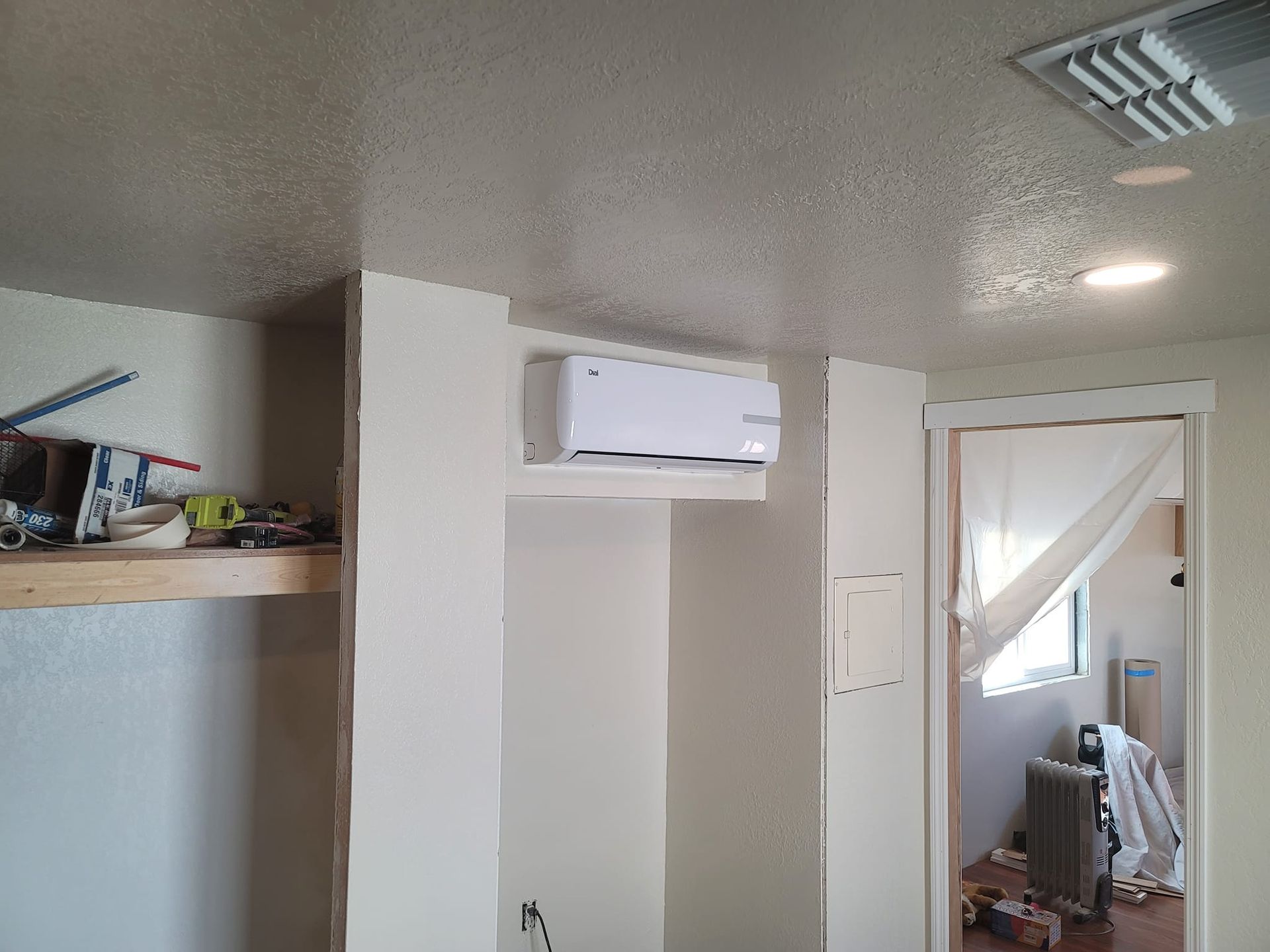 An interior view shows a white mini-split AC unit installed on a white wall.