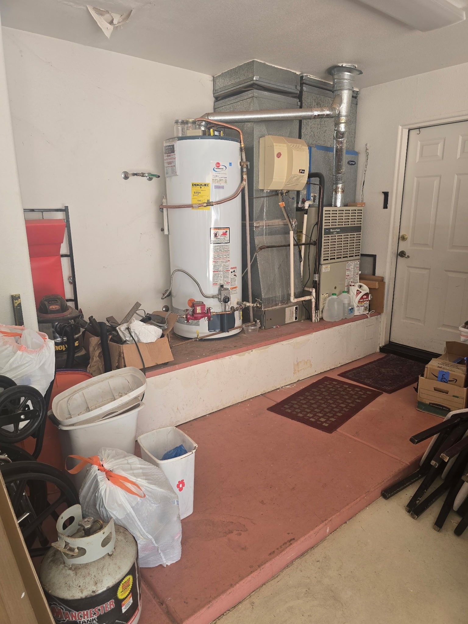 Garage interior with water heater, HVAC unit, and storage.