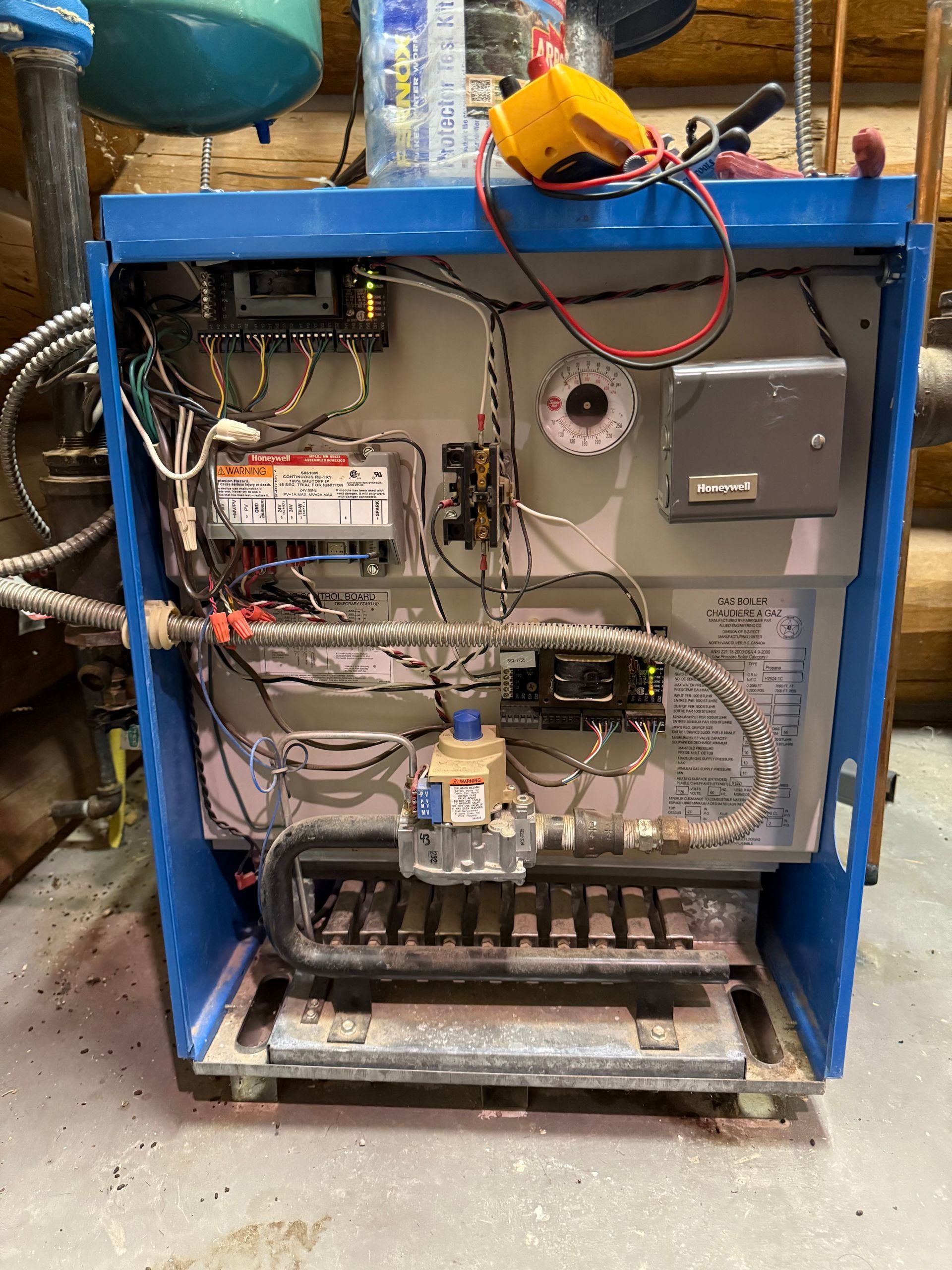The inside of a blue boiler with a lot of wires coming out of it.