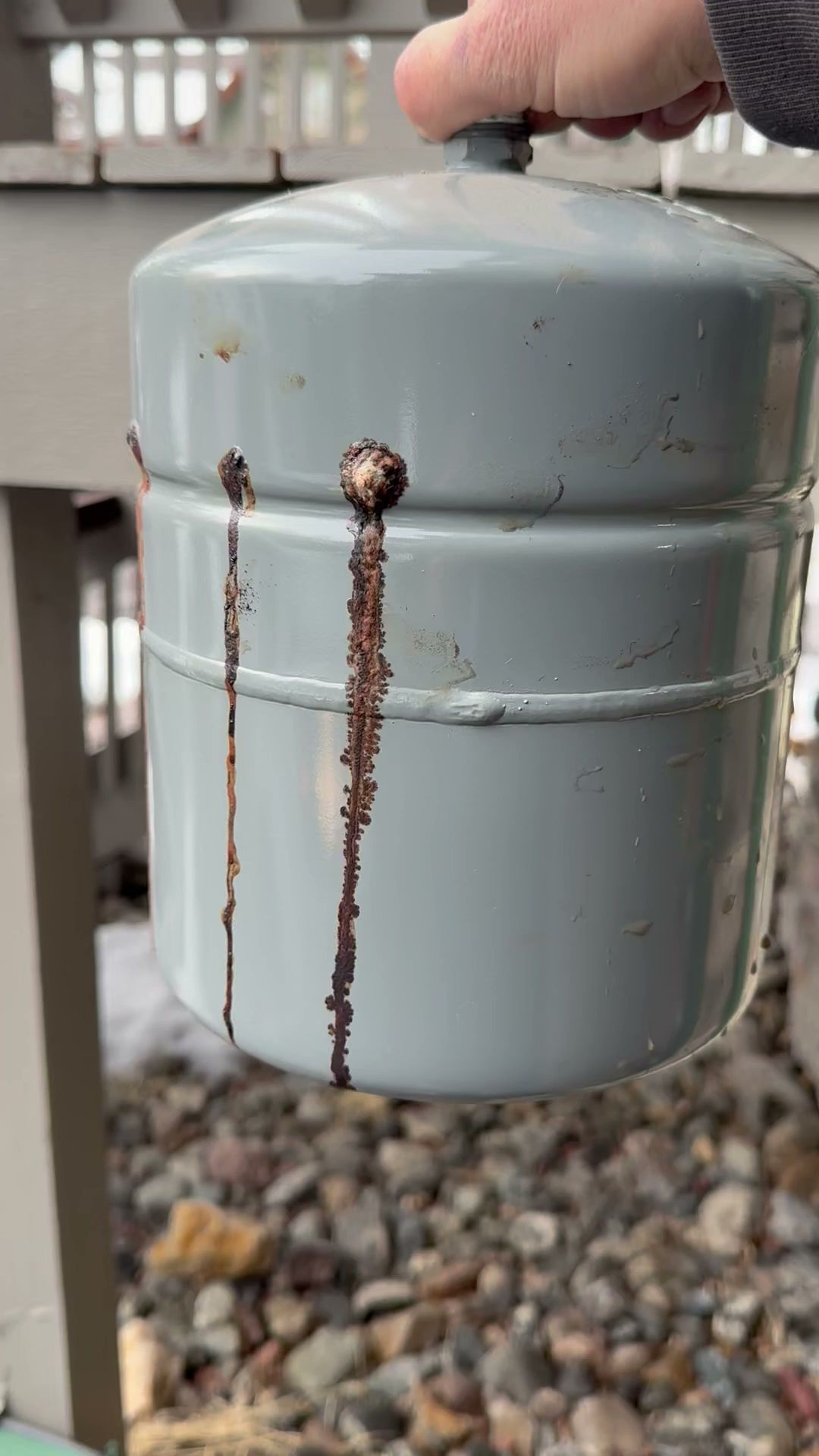 A person is holding a metal container with rust coming out of it.