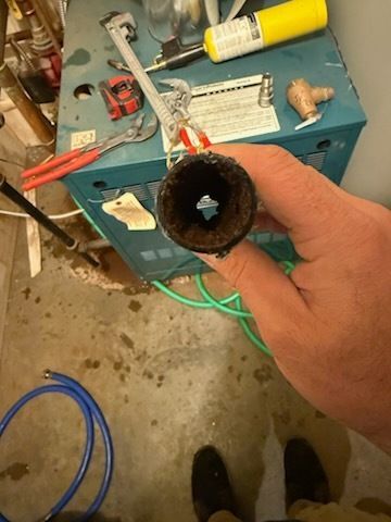 A person is holding a pipe in their hand in front of a machine.