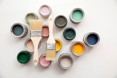 a bunch of paint cans and brushes on a white surface .