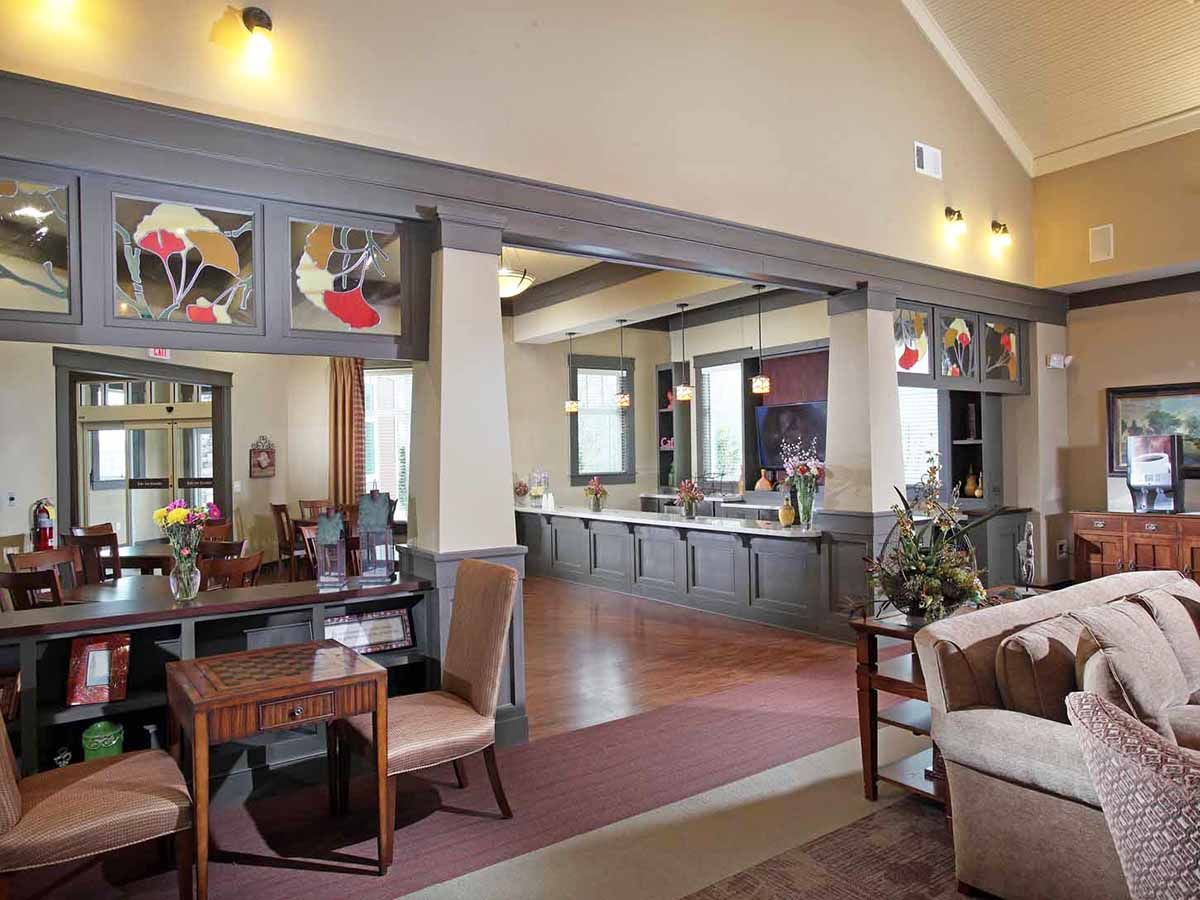 Spacious community lounge with a long service counter, seating, and decorative columns.