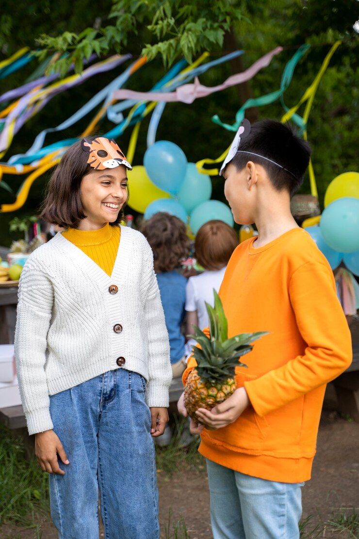 A boy and a girl are standing next to each other holding pineapples.