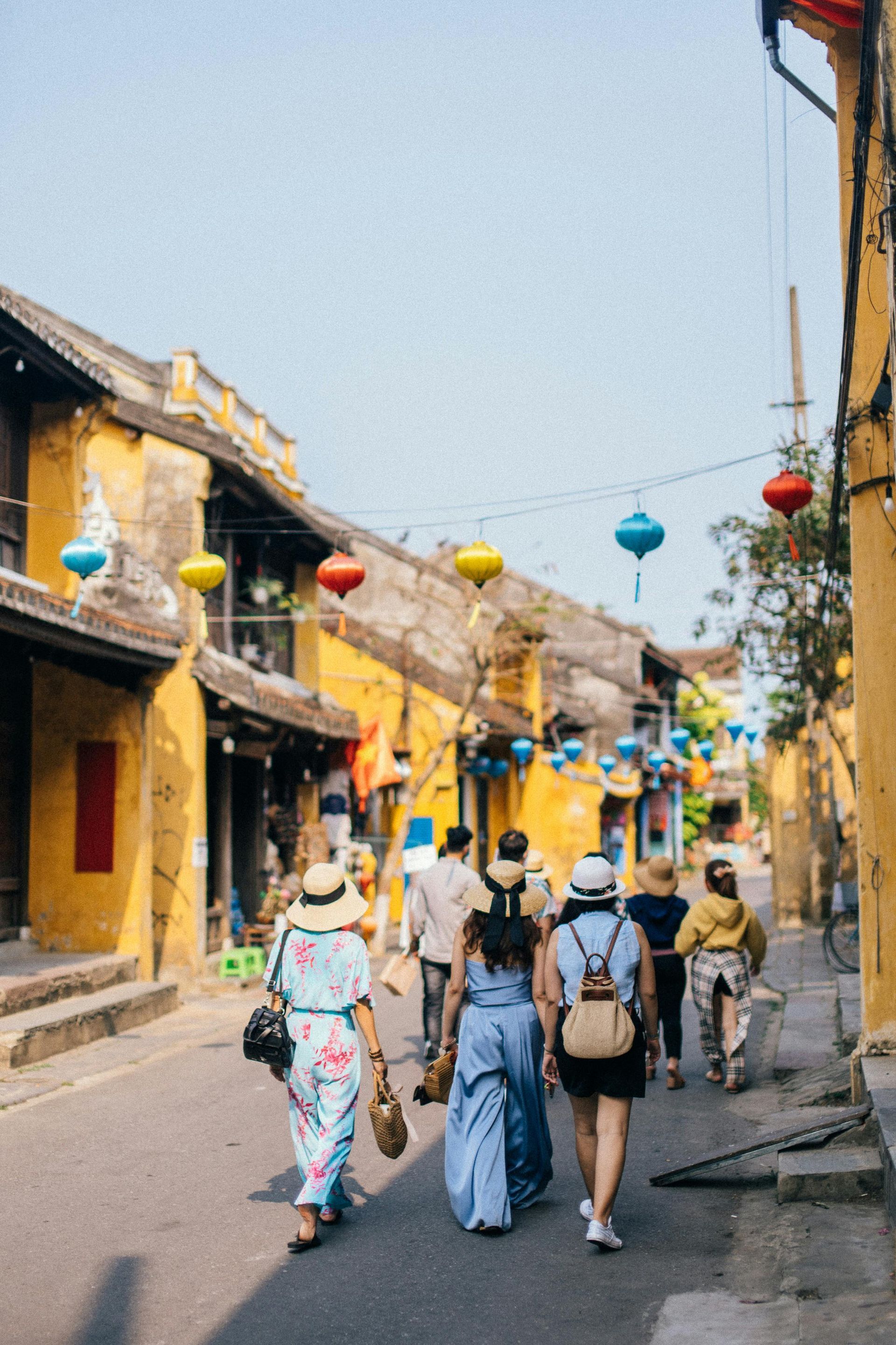 A group of people are walking down a street with lanterns hanging from the buildings.