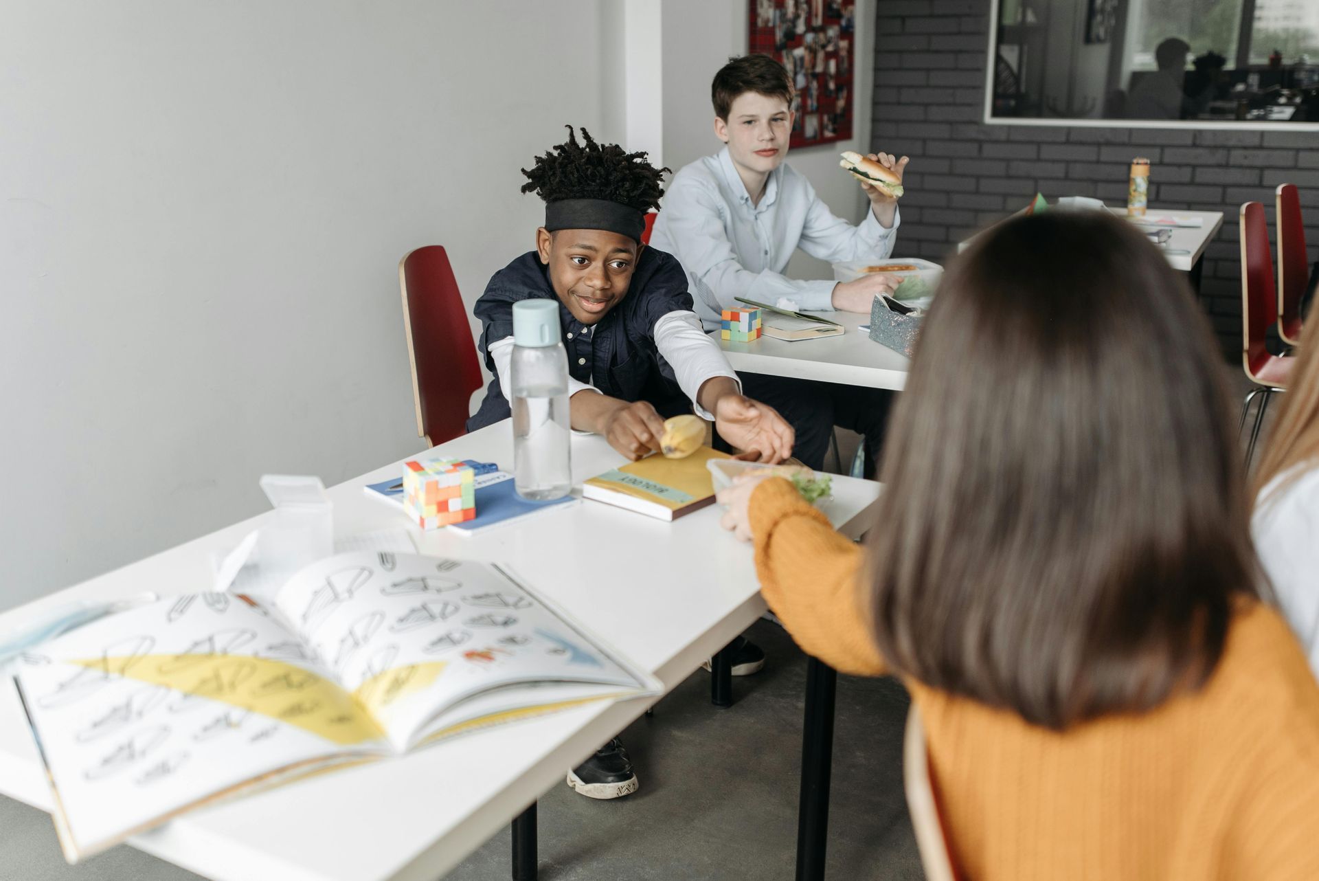 A group of young people are sitting at a table in a classroom.