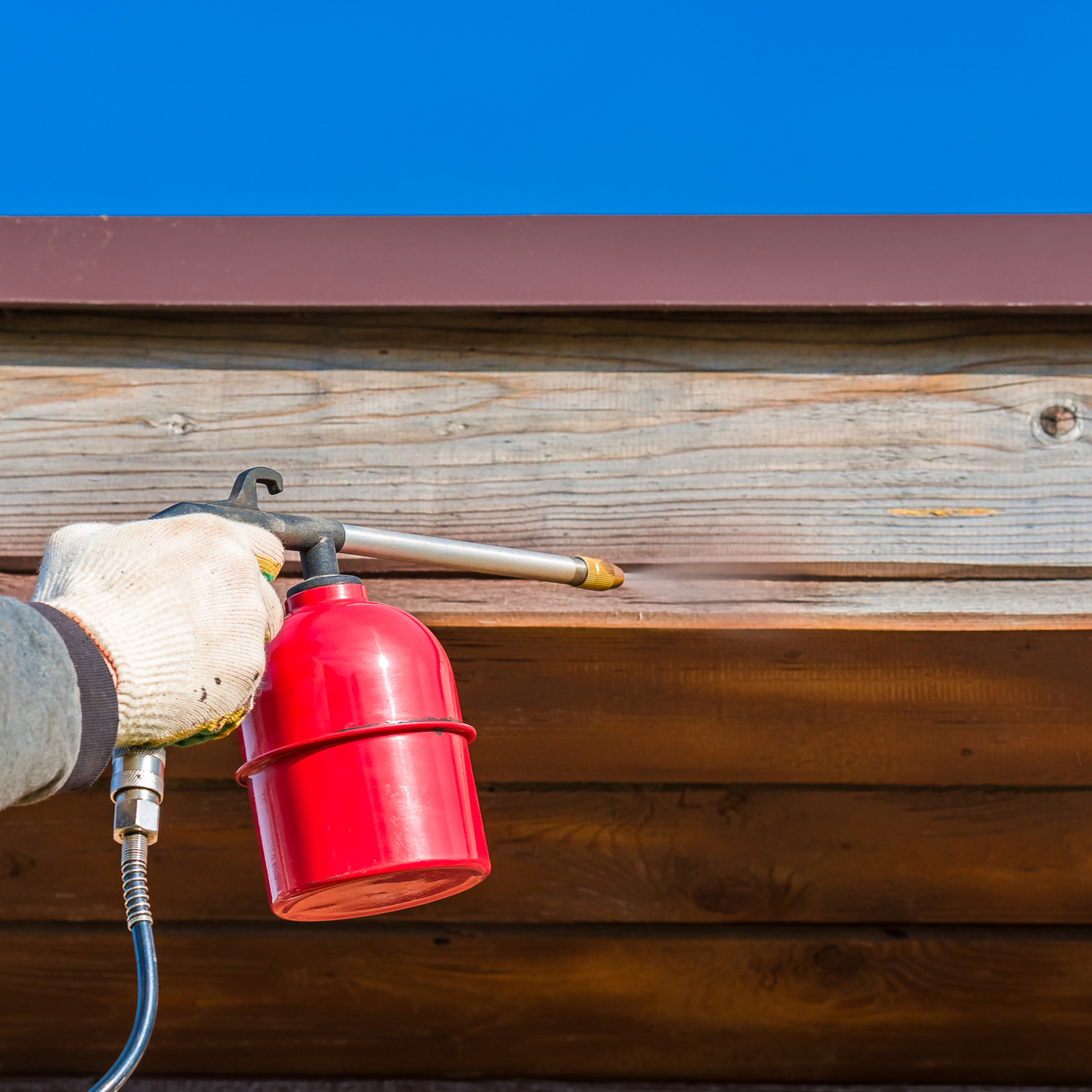 A person is spraying a wooden surface with a spray for termite services
