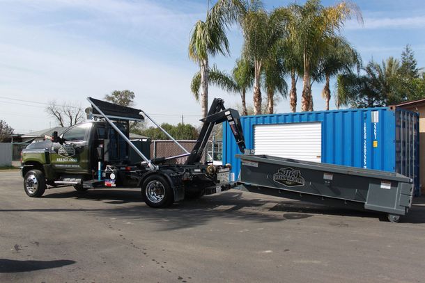 A blue dumpster filled with trash is parked on the side of the road.