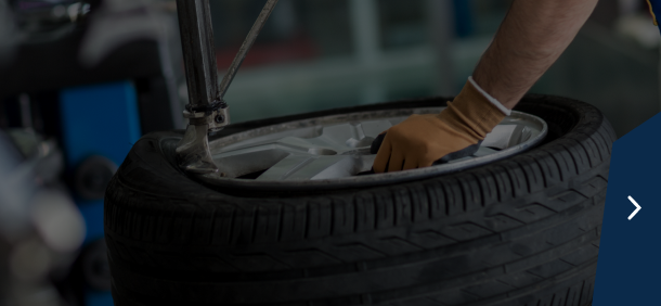 Close-up of truck tires in a garage setting with a dark blue sidebar and a right arrow | Marshside Motors