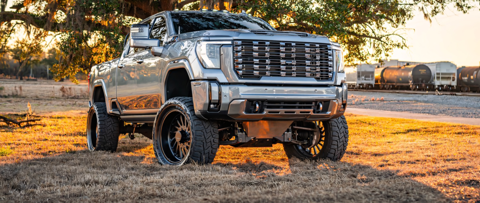 Two lifted pickup trucks driving on a highway. One is silver, the other is black | Marshside Motors