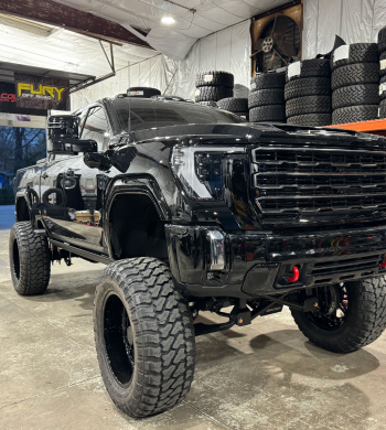 Black lifted GMC truck with large tires in a garage | Marshside Motors