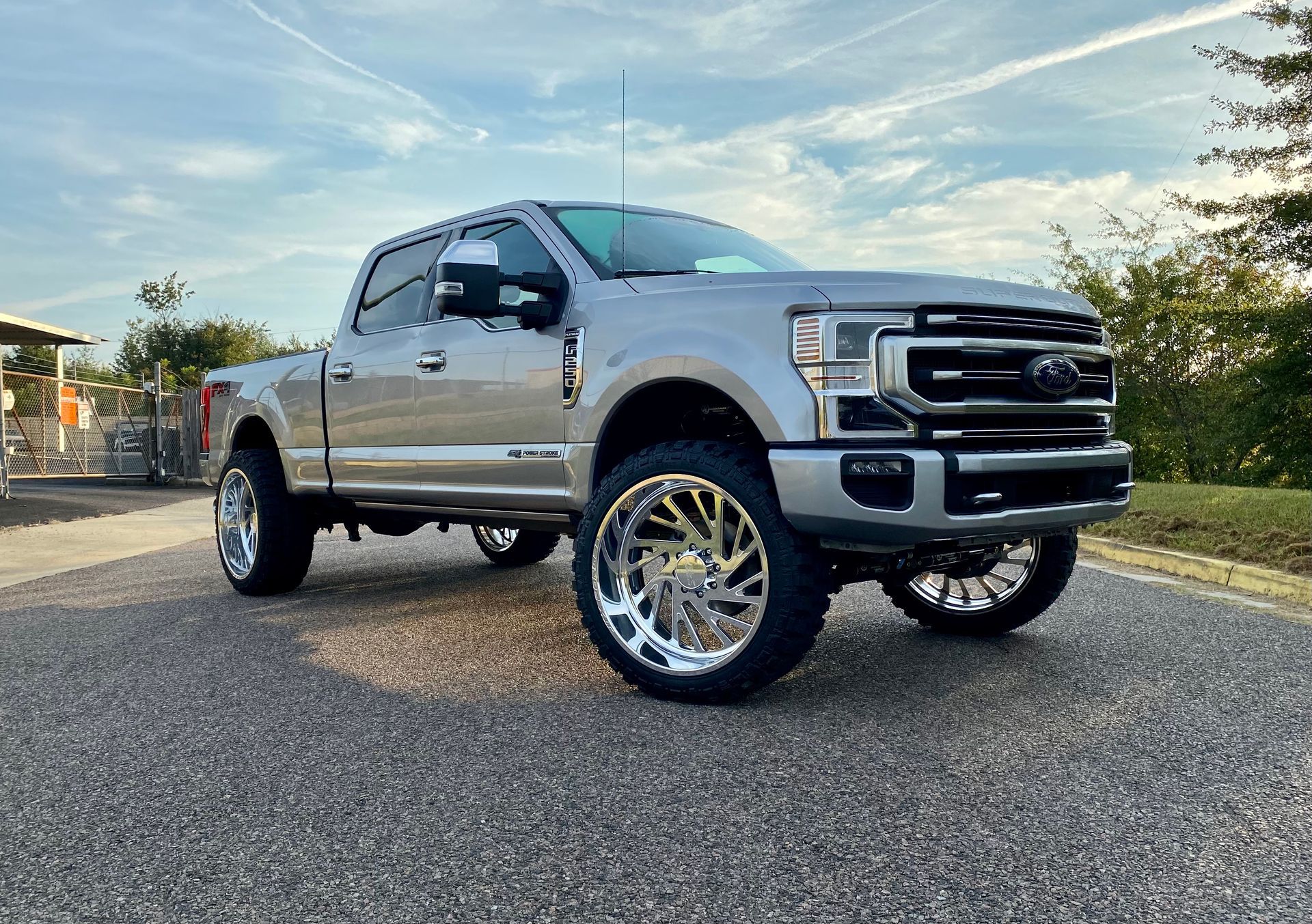 Silver Ford F-series truck with large chrome wheels parked outdoors on asphalt, with a cloudy sky | Marshside Motors