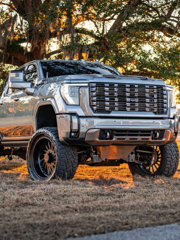 Black truck driving on a bridge, with a blurred background of the sky and structures | Marshside Motors