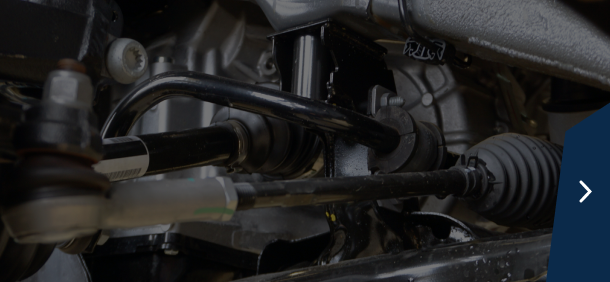 Close-up of truck tires in a garage setting with a dark blue sidebar and a right arrow | Marshside Motors