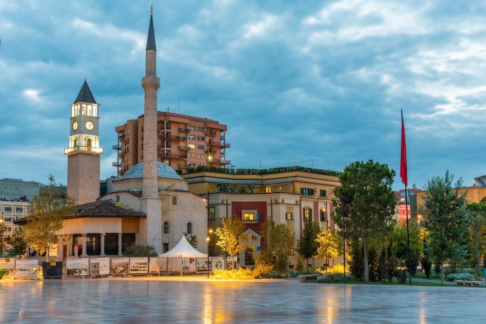Mosque and tower in Tirana, Albania, at dusk; buildings in the background.