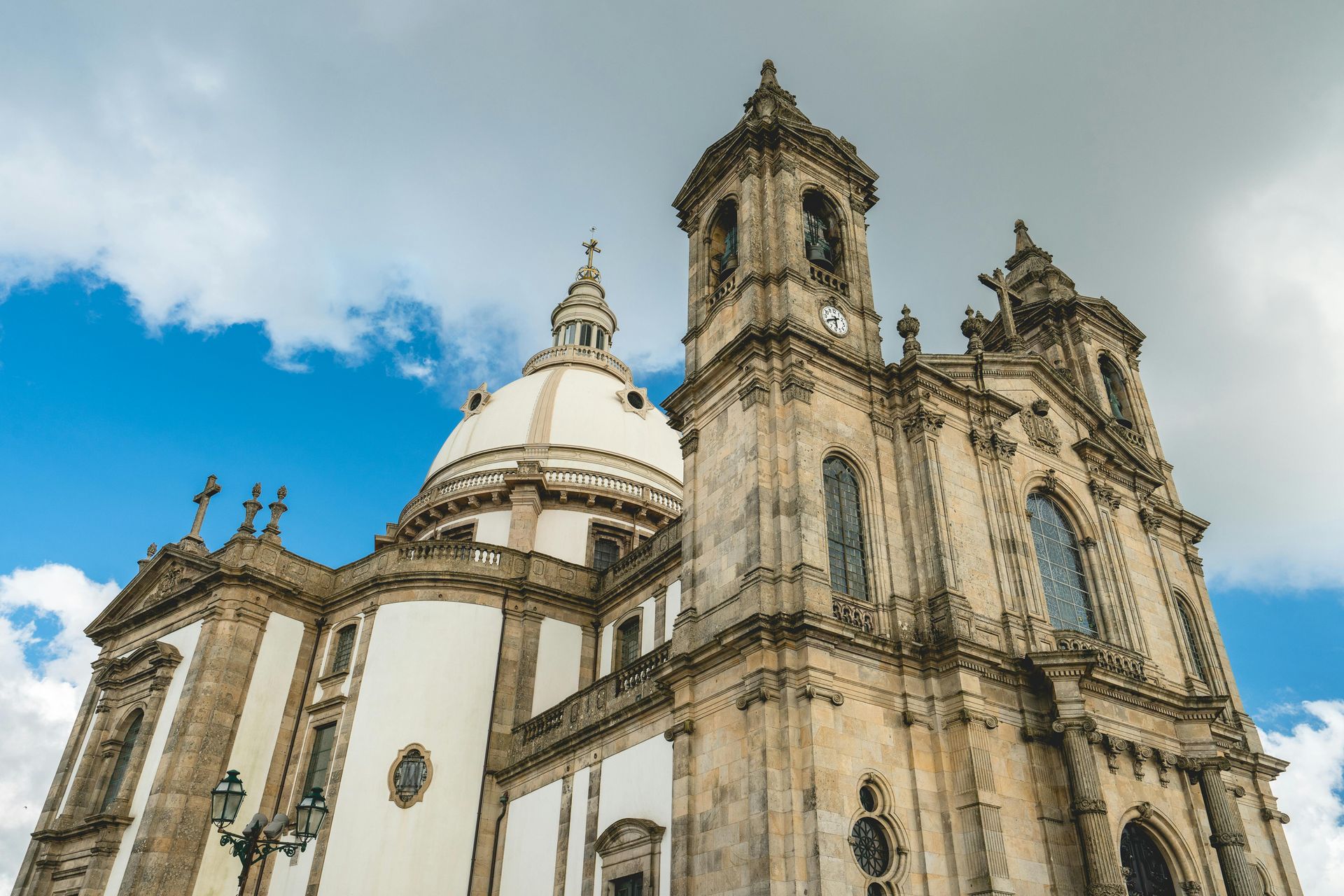 Ornate beige cathedral with towers and dome against a blue sky with clouds.