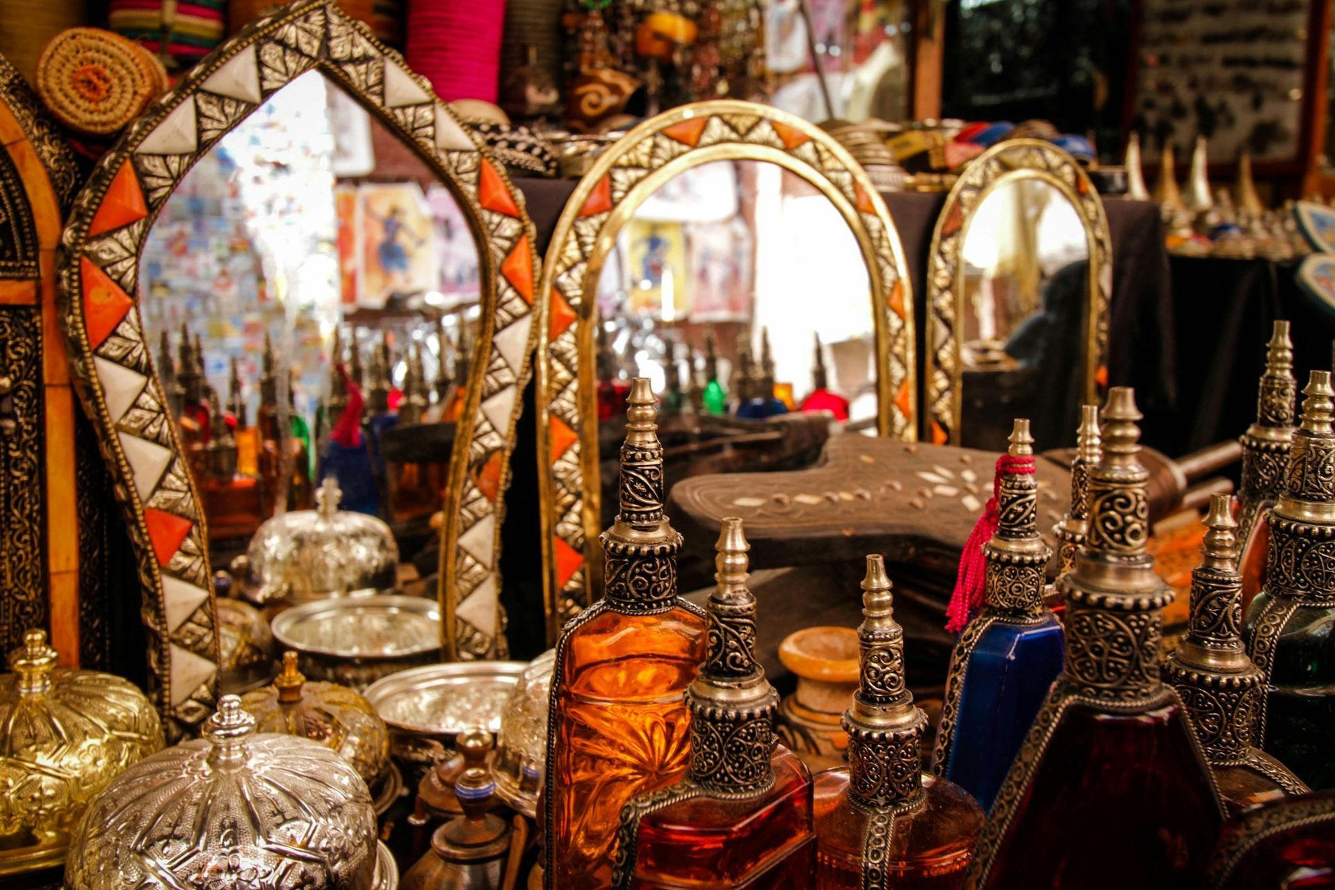 Mirrors, ornate bottles, and silver containers on display at a market.