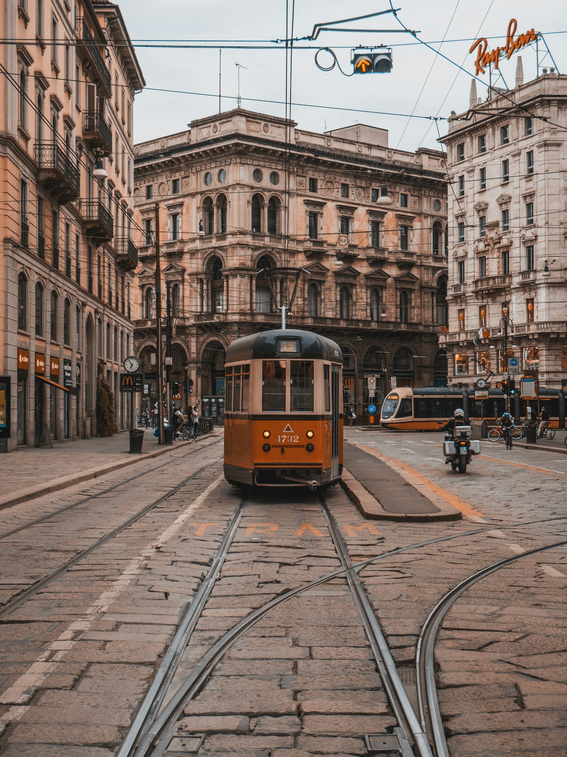 Yellow tram on tracks in a European city street, surrounded by buildings.