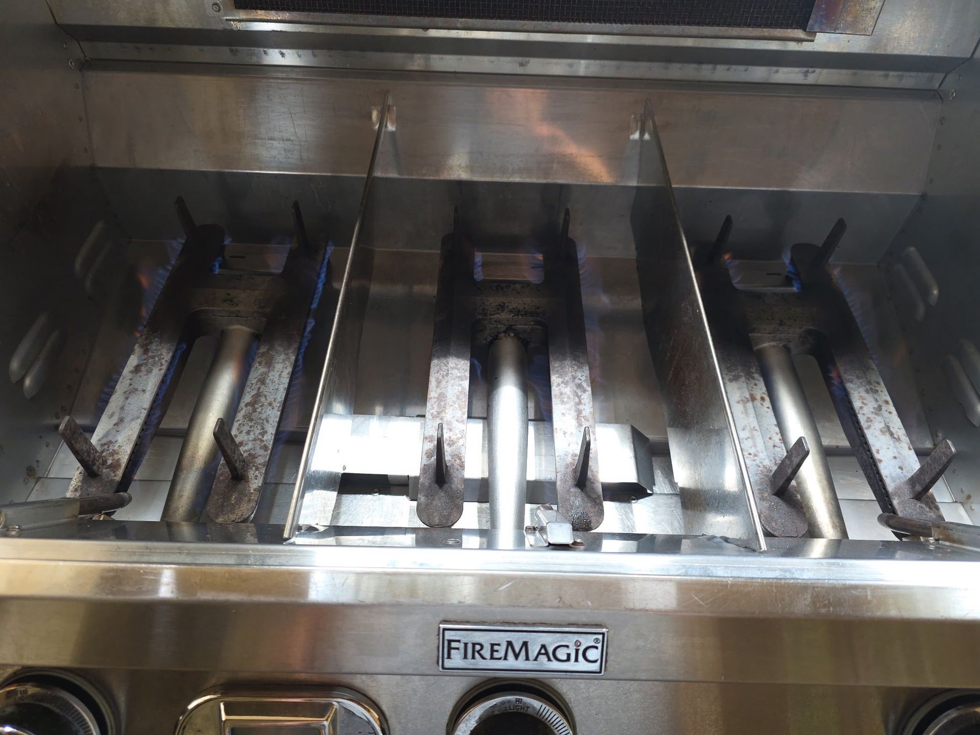FireMagic grill interior with three burners and stainless steel finish.